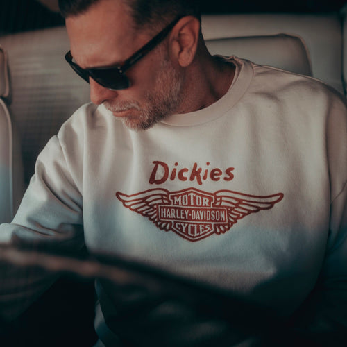 Man wearing a Dickies sweatshirt with a logo inside a vehicle.