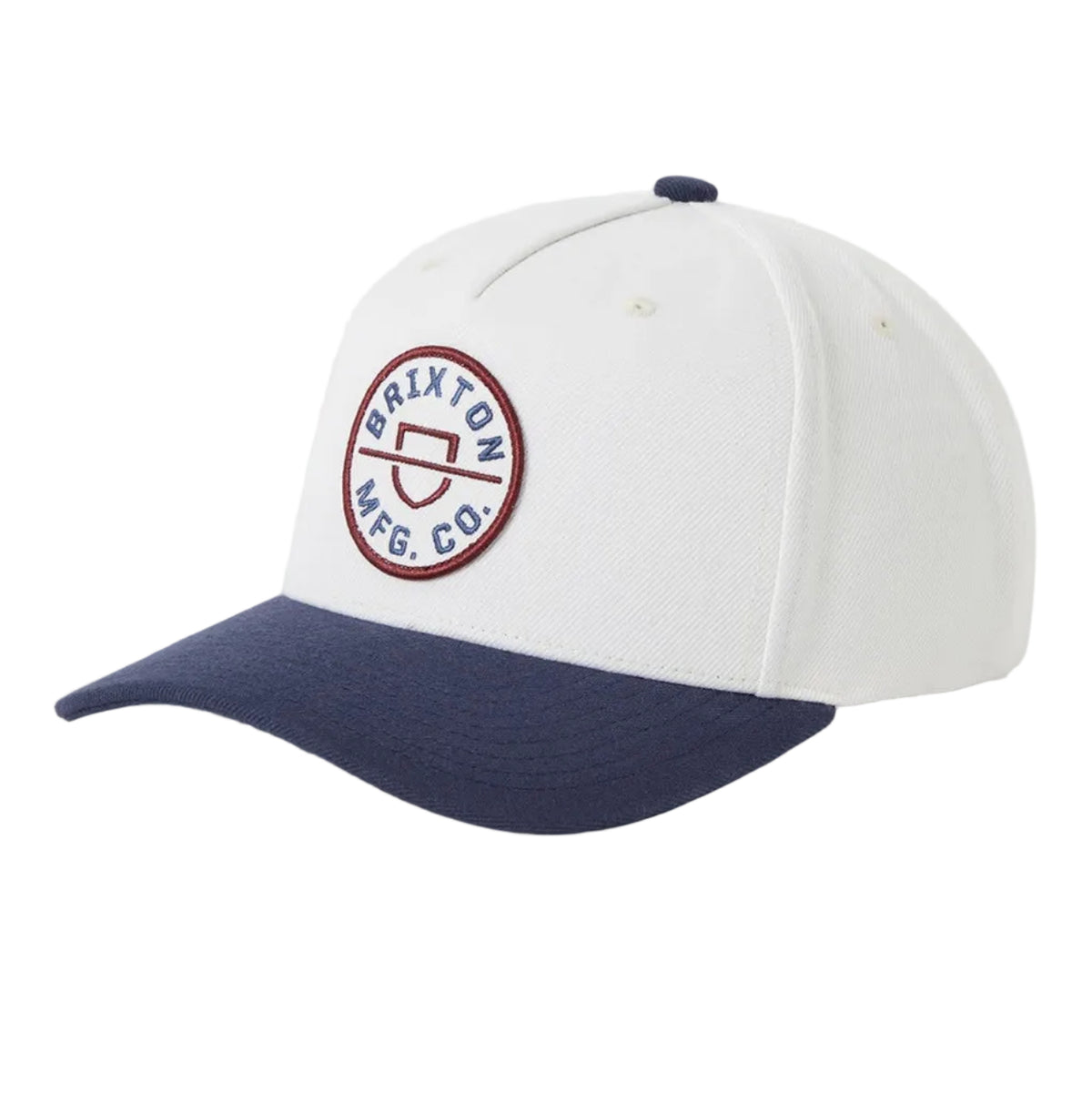 A baseball cap with a white crown and a navy blue curved brim, featuring a circular embroidered logo on the front that reads Brixton MFG CO