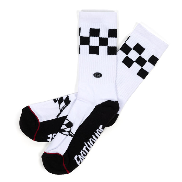 A pair of white crew socks with black checkerboard patterns near the top, black toe and heel sections, and the word 'FASTHOUSE' printed in white on the sole, shown on a plain white background.