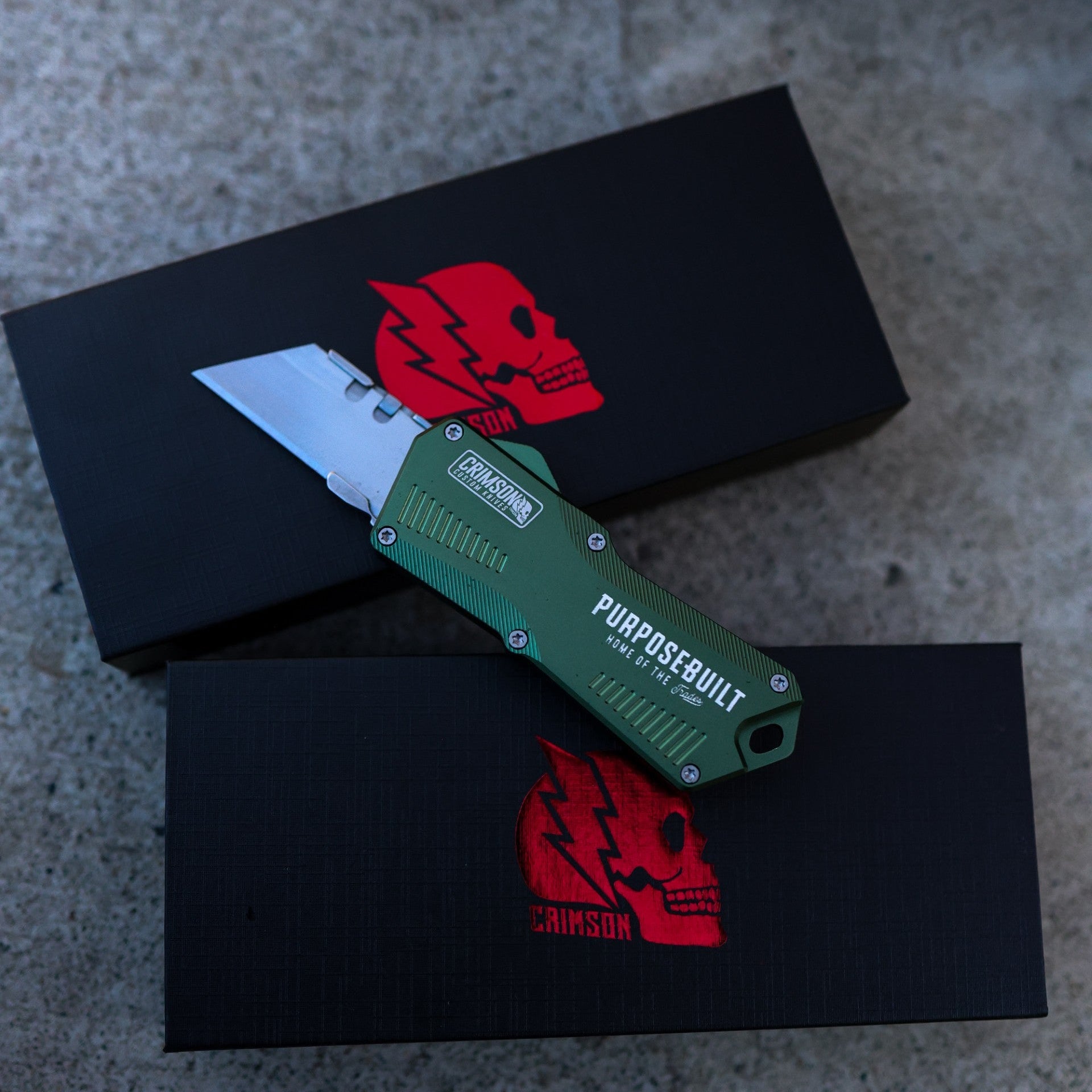 Green pocket knife with 'Purposely Built' branding on a black box with red logo.